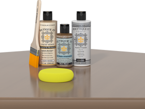 Retique It® Light Wood kit with brush, Wood’n Primer, gloss top coat, and yellow sponge on a reflective surface.