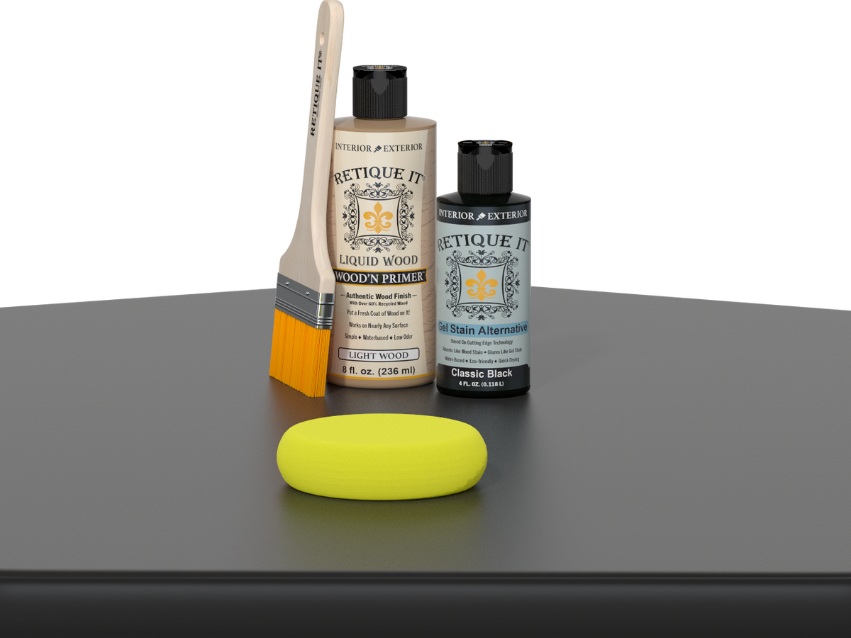Retique It® Classic Black Kit with Light Wood’n Primer, Classic Black Gel Stain Alternative, paintbrush, and yellow sponge on a black tabletop.