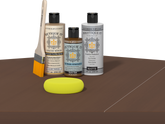 Retique It® Light Wood Wood’n Primer with Dark Oak Gel Stain Alternative, matte topcoat, brush, and yellow sponge on a dark tabletop.