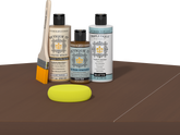 Retique It® Light Wood Wood’n Primer with Dark Oak Gel Stain Alternative, matte topcoat, brush, and yellow sponge on a tabletop.