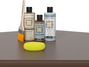 Retique It® Light Wood Wood’n Primer with Dark Oak Gel Stain Alternative, satin topcoat, brush, and yellow sponge on a tabletop.