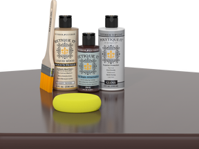 Retique It® Light Wood Wood’n Primer with Java Gel Stain Alternative, gloss topcoat, brush, and yellow sponge on a reflective tabletop.