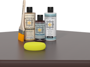 Retique It® Light Wood Wood’n Primer with Java Gel Stain Alternative, satin topcoat, brush, and yellow sponge on a tabletop.