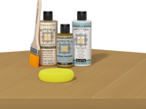 Retique It® Light Wood Wood’n Primer with Old Oak Gel Stain Alternative, matte topcoat, brush, and yellow sponge on a tabletop.