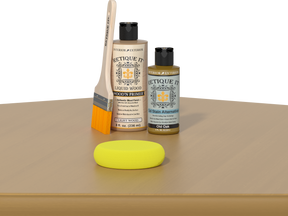 Retique It® Old Oak Kit with Light Wood’n Primer, Old Oak Gel Stain Alternative, paintbrush, and yellow sponge on an oak tabletop.