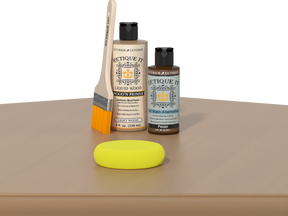 Retique It® Dark Pecan Kit with Light Wood’n Primer, Pecan Gel Stain Alternative, paintbrush, and yellow sponge on a wood tabletop.