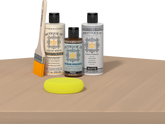 Retique It® Pecan Multipurpose Kit contents with Bleached Wood Liquid Wood primer, Pecan gel stain alternative, PolyTique It® matte exterior top coat, paintbrush, and yellow sponge displayed on a light wood surface.