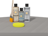 Retique It® Weathered Wood Multipurpose Kit contents with Light Wood Liquid Wood primer, Weathered Wood gel stain alternative, PolyTique It® matte exterior top coat, paintbrush, and yellow sponge displayed on a gray wood surface.