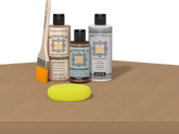 Retique It® Pecan Multipurpose Kit contents with Light Wood Liquid Wood primer, Pecan gel stain alternative, PolyTique It® matte exterior top coat, paintbrush, and yellow sponge displayed on a wood surface.