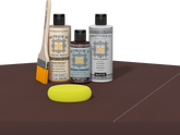 Retique It® Light Wood Wood’n Primer with Red Mahogany Gel Stain Alternative, matte topcoat, brush, and yellow sponge on a dark tabletop.