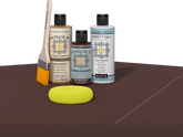 Retique It® Light Wood Wood’n Primer with Red Mahogany Gel Stain Alternative, matte topcoat, brush, and yellow sponge on a dark tabletop.