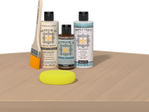 Retique It® Pecan Multipurpose Kit contents with Bleached Wood Liquid Wood primer, Pecan gel stain alternative, Tripletique matte top coat, paintbrush, and yellow sponge displayed on a light wood surface.