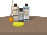 Retique It® Barn Wood Multipurpose Kit contents with Light Wood Liquid Wood primer, Barn Wood gel stain alternative, Tripletique matte interior top coat, paintbrush, and yellow sponge displayed on a wood surface.