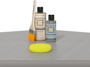 Retique It® Weathered Wood Kit with Light Wood’n Primer, Weathered Wood Gel Stain Alternative, paintbrush, and yellow sponge on a weathered wood tabletop.