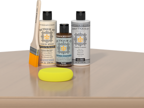 Retique It® White Oak kit with brush, Wood’n Primer, Pecan stain alternative, gloss top coat, and yellow sponge on a wood surface.