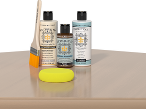 Retique It® White Oak kit with brush, Wood’n Primer, Pecan stain alternative, gloss top coat, and yellow sponge on a wood surface.