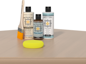 Retique It® White Oak kit with brush, Wood’n Primer, Pecan stain alternative, satin top coat, and yellow sponge on a wood surface.