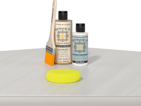Retique It® Light Wood Wood’n Primer with White Wash Gel Stain Alternative, brush, and yellow sponge on a white tabletop.