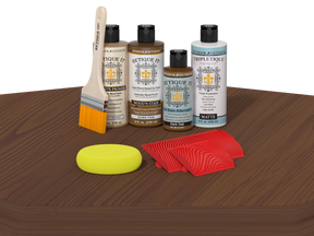 Set of wood care products including bottles, a brush, a sponge, and cloths on a wooden surface.