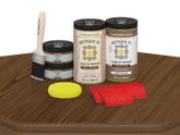 Retique It® Modern Walnut Wood Kit with primer, stain, brush, yellow sponge, and red graining tools on a wood tabletop.