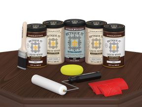 Retique It® Java Wood'n Kit featuring Java Liquid Wood stain, Light Wood primer, Java Gel Stain Alternative, paint brush, white roller, yellow sponge, and red graining tools displayed on a dark wood tabletop.