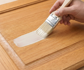 Retique It® Bleached Wood Kit primer being brushed onto a wood cabinet door.