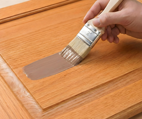 Retique It® Dark Wood Kit primer being brushed onto a wood cabinet door.