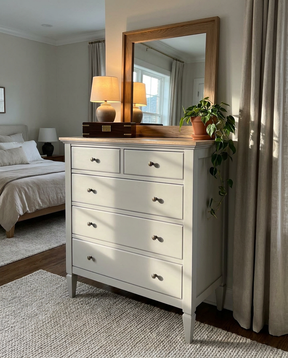 White dresser with wooden top in a bedroom setting