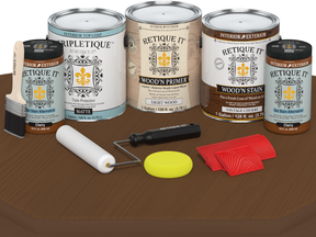 Retique It wood care products including cans, a brush, roller, and applicators on a wooden surface.
