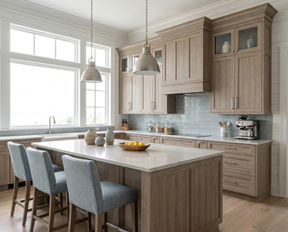 A bright, modern kitchen featuring light oak wood cabinets, a matching island with a white stone countertop, three gray upholstered bar stools, and a light blue tile backsplash.