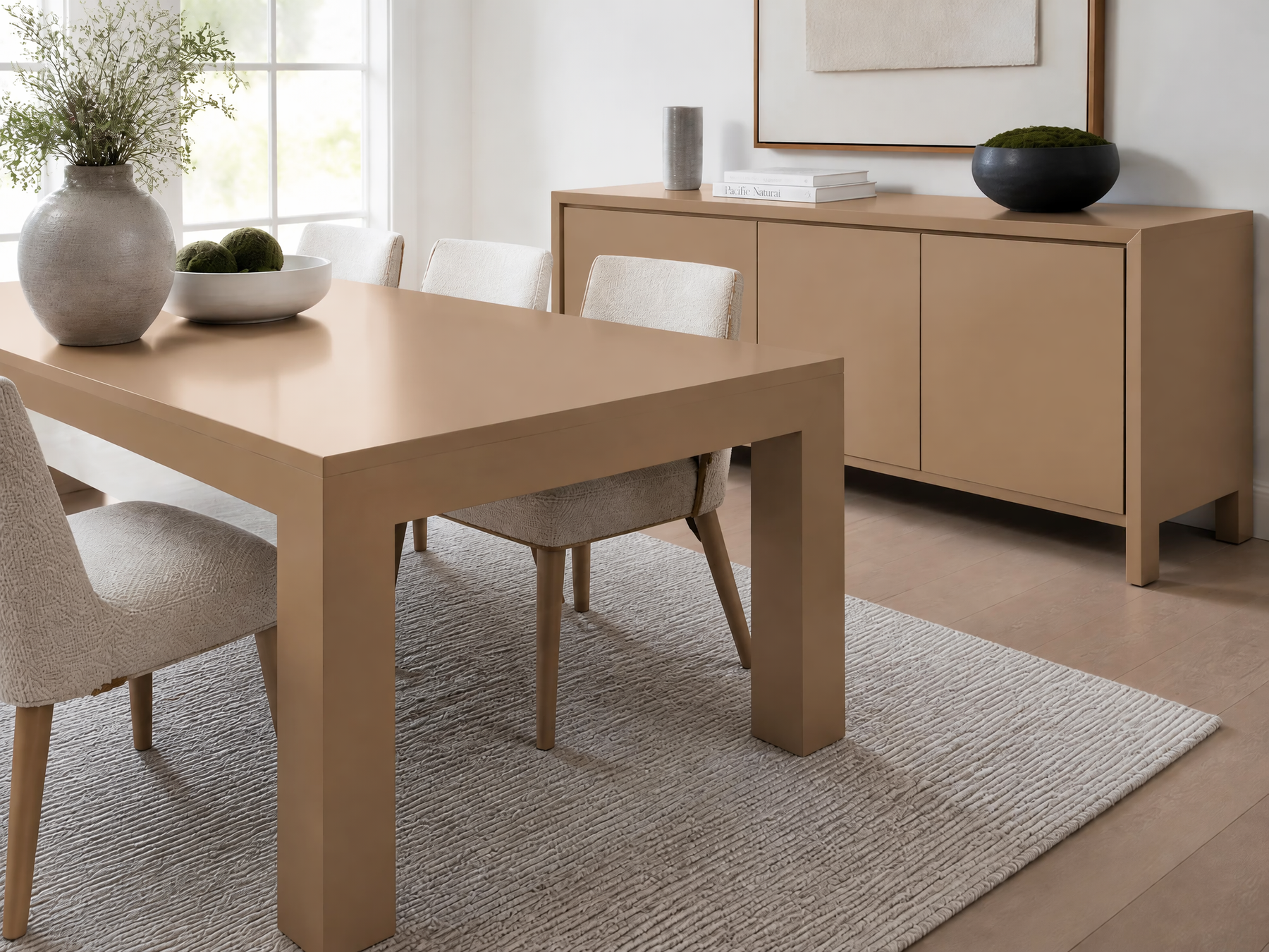 Dining room with a glossy tan table, upholstered chairs, matching sideboard, and neutral decor.