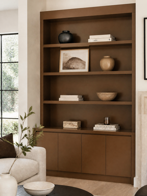 Dark brown built-in shelving and cabinets styled with books, pottery, and framed artwork in a modern living room.
