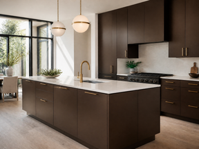 A modern kitchen featuring dark brown cabinetry with gold handles, a white marble island countertop, a gold gooseneck faucet, and a black gas range. The space is illuminated by two spherical pendant lights and natural light from a large window on the left.