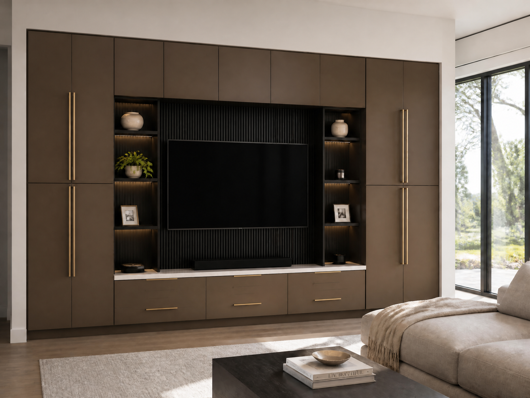 A modern wall-mounted entertainment center in a living room setting. The unit features dark brown wood cabinets with slim gold handles, open shelves with built-in lighting, a black ribbed central panel, and a white marble-look front apron.