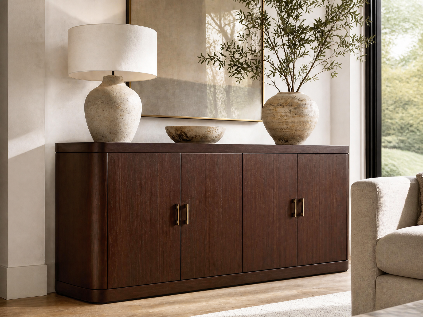 Dark walnut four-door sideboard with brass handles, styled with ceramic decor and a table lamp.