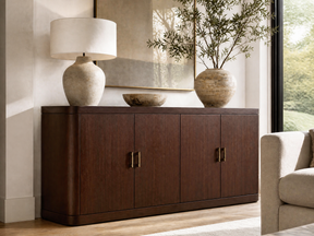 Dark walnut four-door sideboard with brass handles, styled with ceramic decor and a table lamp.